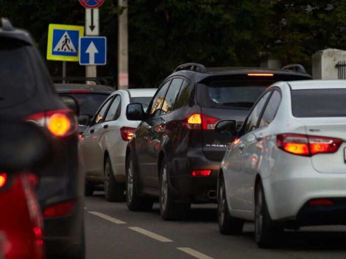 Veículos circulam próximos uns dos outros em uma rua movimentada, cenário que remete às situações de trânsito que podem resultar em infrações e multas.