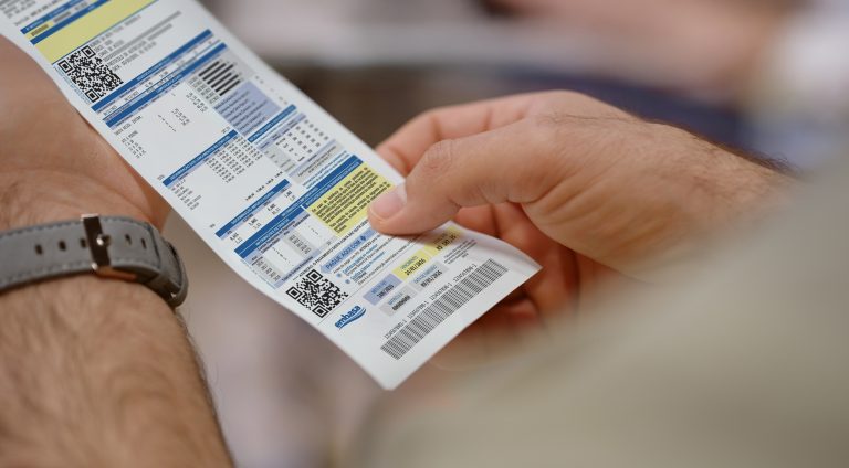 Cash register, receipt paper and man holding financial payment pill for price and cost check. Bookkeeping document, banking balance and retail shopping information of shop debt after buying product