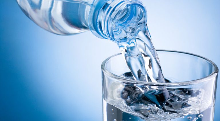 Pouring,Water,From,Bottle,Into,Glass,On,Blue,Background