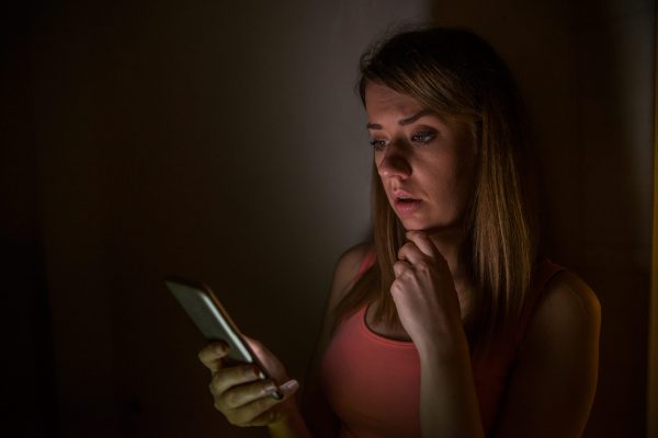 Doubtful woman looking down and wondering if she must call on the phone or waiting for a message