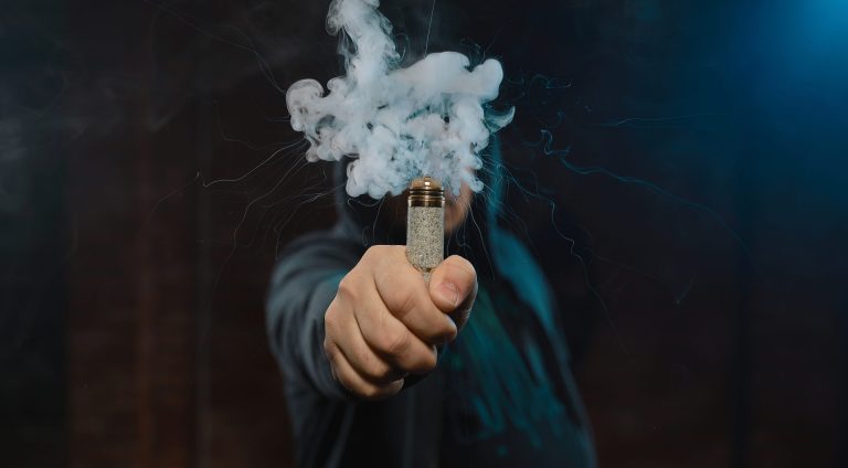 Dripper in one hand making a cloud of white, blue vapours. Friendly for vape shop posters and design. Vaping concept.