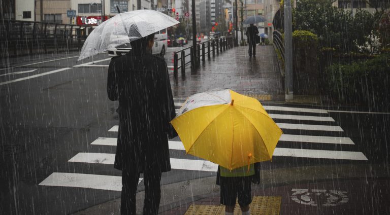 Family crossing a road on rainy day