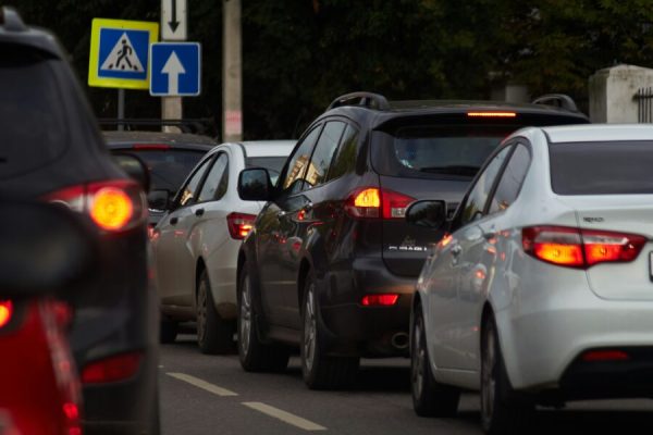 Veículos circulam próximos uns dos outros em uma rua movimentada, cenário que remete às situações de trânsito que podem resultar em infrações e multas.