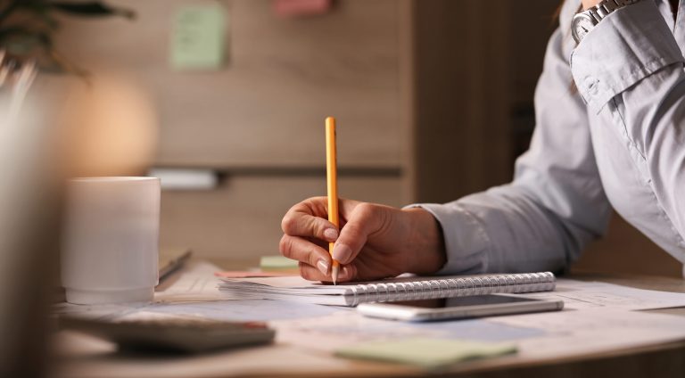 Unrecognizable businesswoman working in the office and writing business plans in her notebook.