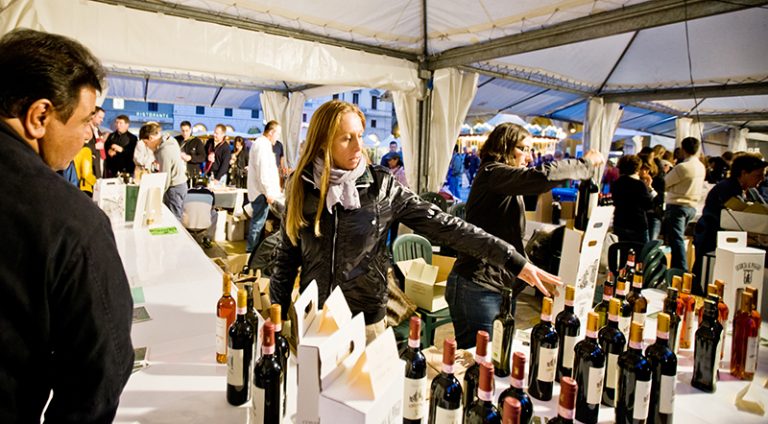 Florence, Italy - October 7, 2011: Outdoor Wine and Food Fair "Emozioni dal Chianti", Florence, Italy. Regular Food and Wine Festival taking place in Florence, demonstrating wines and food from few municipalities of Toscana. Shot made at the evening at Piazza Repubblica. People visiting event to taste and buy food and wine.